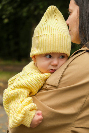 Mother Holding Baby in Yellow Outfit at Park