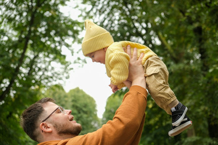 Father Lifting Baby in Park