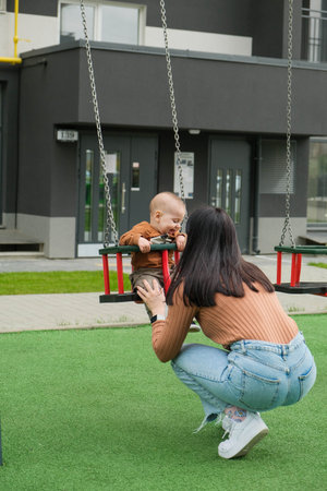 Mother and Baby on Swing in Playgroundの写真素材