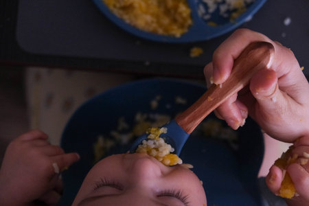 Baby Eating Rice and Eggs with Spoonの写真素材