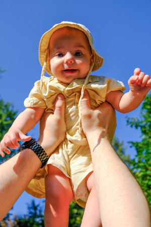 Joyful Baby Lifted in the Air Outdoorsの写真素材