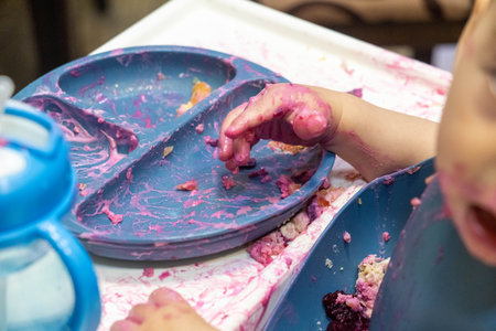 Baby Enjoying a Messy Meal in High Chairの写真素材