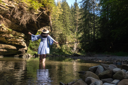 Woman Strolling by River in Forestの写真素材