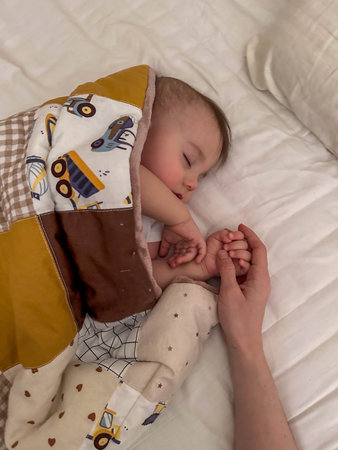 Peaceful sleeping baby holding adult hand