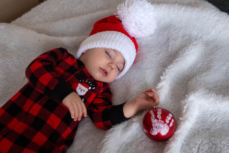 Sleeping baby in santa hat with christmas ornament