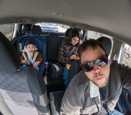 Family road trip selfie inside car with toddler in safety seatの写真素材