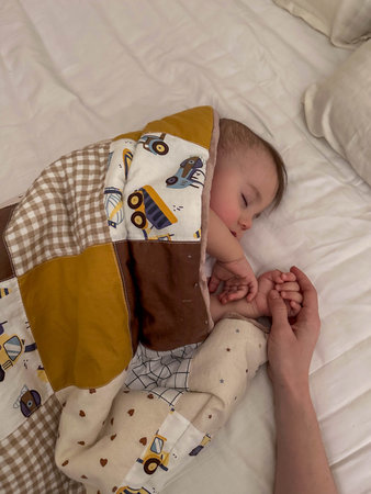 Peaceful sleeping baby holding adult hand