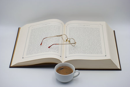 A book with glasses and a cup of coffee on a white backgroundの写真素材