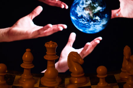 Close-up of human hands playing chess with Earth on background.の写真素材