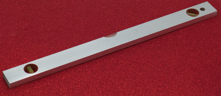 Close-up of a metal spirit level on a red background.