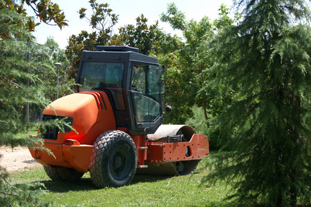 tractor with a bucket on a background of green trees and bushes
