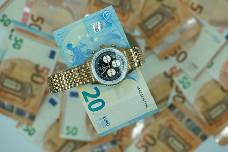 Time is money. Wristwatch on euro banknotes background.の写真素材