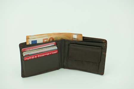 Leather wallet with banknotes and credit cards on white background.
