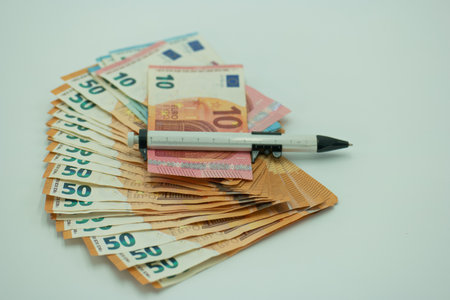 Euro banknotes and a pen on a white background. selective focus.