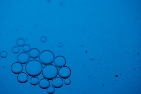 Macro shot of oil bubbles on a blue background with copy space