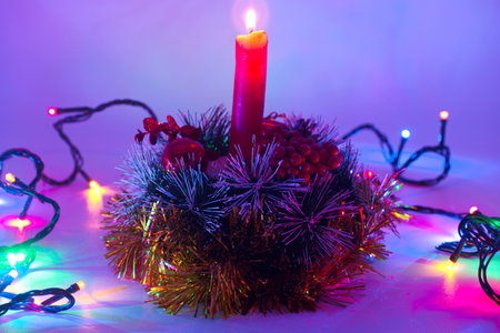 Christmas candle in a basket with tinsel and lights on a white backgroundの写真素材