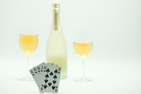 Champagne bottle and two pairs of playing cards on white background.の写真素材
