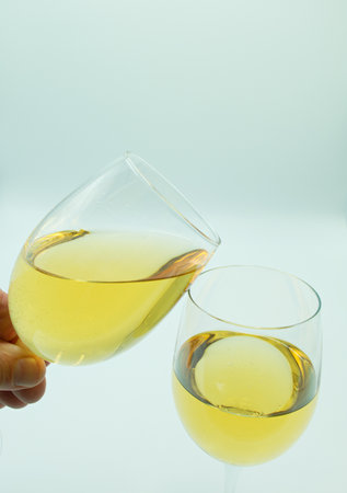 Two glasses of white wine in hand on a white background with copy spaceの写真素材