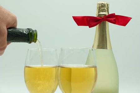 Bottle of champagne and two glasses with red ribbon on white backgroundの写真素材