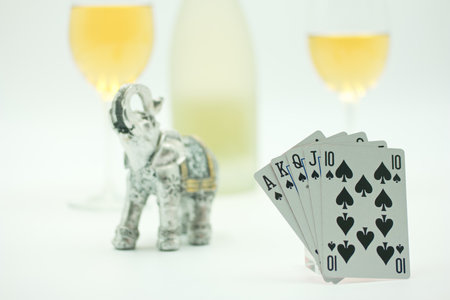 Playing cards, elephant and two glasses of wine on a white background
