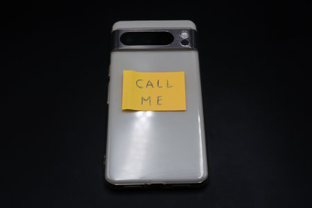 a mobile phone with information stuck on a sticky note on a black background