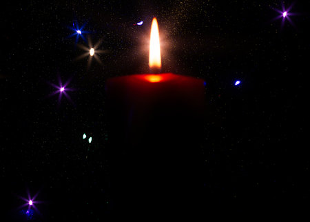 Burning candle on dark shiny background atmospheric sceneの写真素材