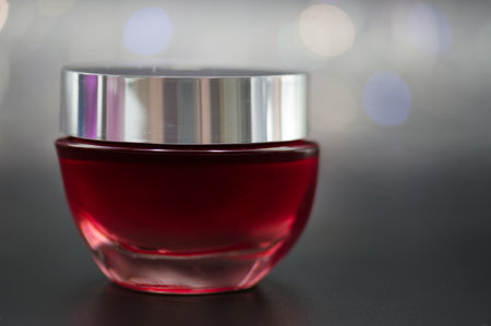 a jar of cosmetic cream on a black background illuminated with colored lightsの写真素材