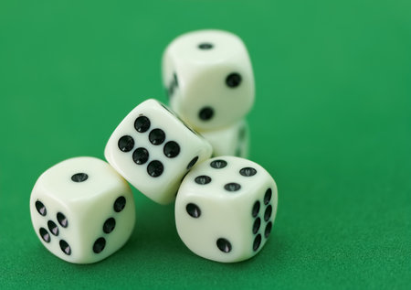 A hand is releasing four dice onto a vibrant green surface, capturing the excitement of a game...