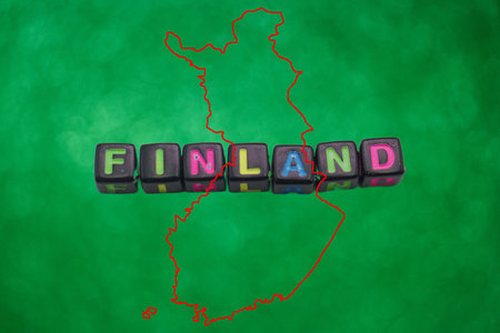 Colorful blocks arranged to spell Finland sit prominently against a bright green background,...