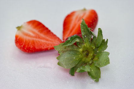 Juicy strawberries are arranged on a clean white surface, showing vibrant red color and glistening droplets, ideal for enhancing dishes or enjoying fresh.の写真素材
