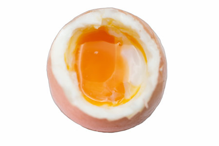 A soft boiled egg, with its shell partially removed, reveals a vibrant yellow yolk surrounded by...