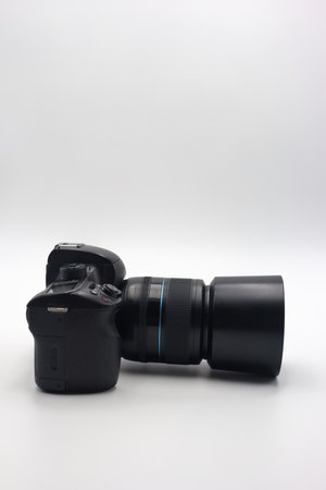 A digital camera is lying on its side with a prominent lens attached, emphasizing its sleek design...
