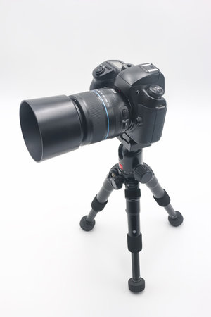 A professional camera is securely mounted on a sturdy tripod, ready to capture high quality images in a white studio environment. The setup offers stability and precision for photography.の写真素材