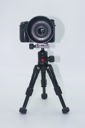 A professional camera mounted on a sturdy tripod stands in a studio with a plain background, indicating preparation for an upcoming photography session.の写真素材