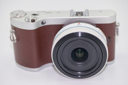 A compact camera showcases a sleek design with a brown leather grip and a prominent wide angle lens. This stylish device captures high quality photos in various settings.の写真素材