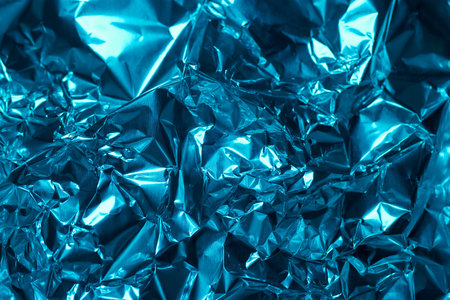 This close up view showcases a strikingly vibrant blue metallic foil, capturing the crumpled texture and light reflections that create depth and complexity. The intricate patterns invite exploration.の写真素材