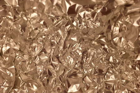 Close up view of shiny crumpled metallic foil, showing intricate creases and reflections. The unique texture creates an interesting visual element suitable for various artistic uses.の写真素材