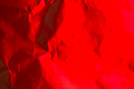 Textured bright red crumpled paper displays a vivid backdrop, perfect for artistic projects, crafts, or decorative uses that draw attention and evoke bold emotions.の写真素材