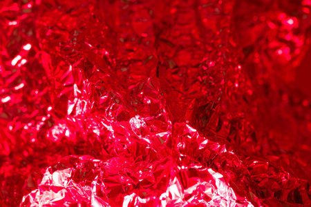 Intricate red metallic foil displays a shiny texture, reflecting light and creating a bold aesthetic. This vivid material can enhance various artistic projects and designs.の写真素材