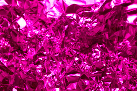 Bright pink crinkled foil fills the space with a dynamic texture and bold color, ideal for creative backgrounds or wrapping. The shiny surface reflects light beautifully.の写真素材