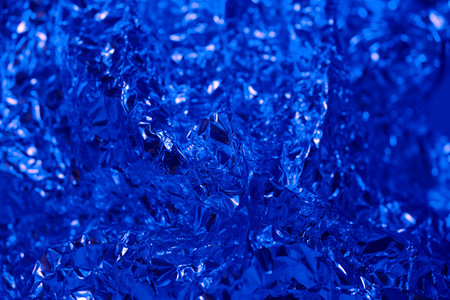 Shiny blue foil creates a textured surface that reflects light in various angles, showcasing intricately designed designs and a vibrant color, ideal for artistic backgrounds.の写真素材