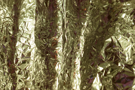 Textured gold foil layered and crinkled reflects light in various shades, creating an eye catching visual effect suitable for art projects and creative backgrounds.の写真素材