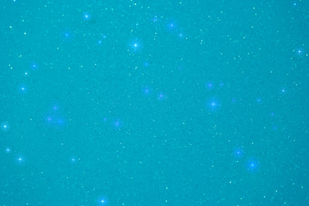 A vast expansion of turquoise background is dotted with sparkling stars, creating a tranquil and enchanting celestial view. This serene display captures the beauty of the night sky.の写真素材