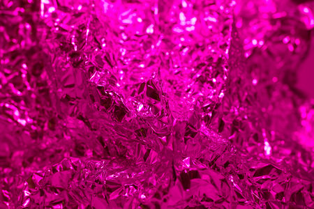 Shimmering pink foil displays a crinkled texture that captures and reflects light. The vibrant colors and shiny surface enhance artistic projects or creative displays.の写真素材
