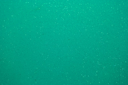 A vibrant emerald green surface showcases a sparkling texture that creates an eye catching backdrop perfect for artistic designs. The shimmering quality adds depth and interest.の写真素材