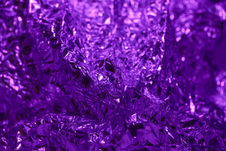 Shimmering purple foil is crumpled to form a textured surface that adds depth, elegance, and a vibrant touch to various artistic and design endeavors.の写真素材