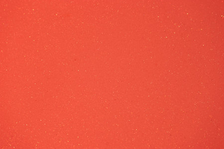 Vivid orange surface showcases sparkling particles that reflect light, making it ideal for artistic creations, crafts, or interior design applications. The texture enhances visual interest.の写真素材