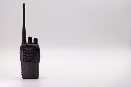 A walkie talkie is placed on a plain surface, showing its compact design and antenna. This device is commonly used for communication in various settings, including outdoor activities and events.の写真素材