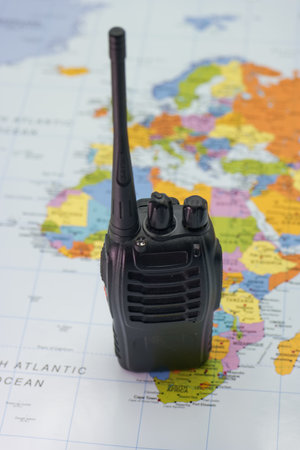 A walkie talkie is placed prominently on a colorful world map, with Africa in the center, showing various countries and oceans clearly visible under natural light.の写真素材