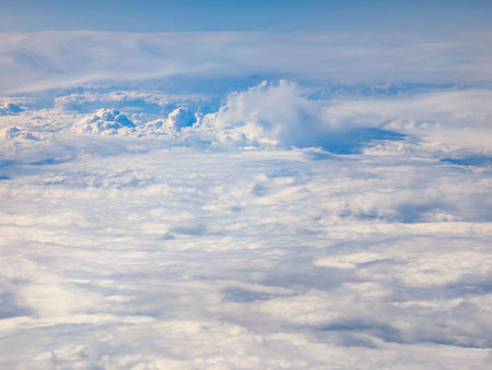 A wide expansion of fluffy clouds stretches across the sky, creating a peaceful and tranquil atmosphere. The bright sunlight illuminates the white clouds, enhancing their beauty.の写真素材